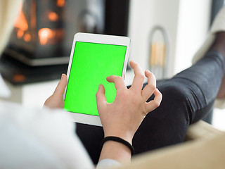 Image showing young woman using tablet computer in front of fireplace