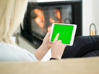 Image showing young woman using tablet computer in front of fireplace