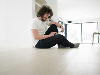 Image showing young man using a tablet at home