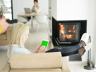 Image showing young woman using tablet computer in front of fireplace