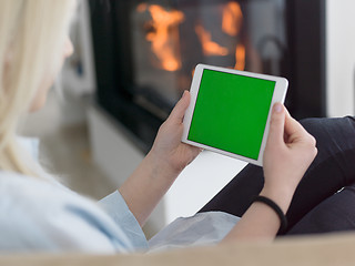 Image showing young woman using tablet computer in front of fireplace