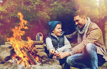 Image showing father and son roasting marshmallow over campfire