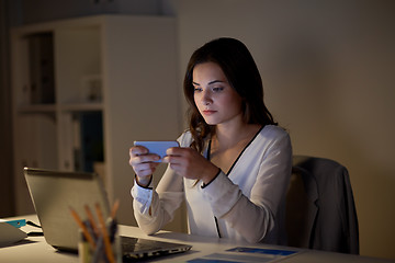 Image showing businesswoman with smartphone and laptop at office