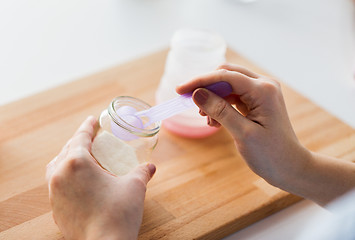 Image showing hands with jar and scoop making formula milk