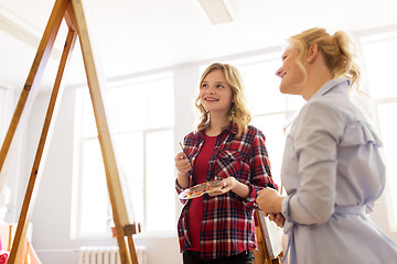 Image showing artists discussing painting on easel at art school