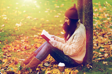 Image showing woman with book drinking coffee in autumn park
