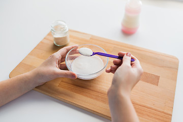 Image showing hands with spoon and jar making baby cereal