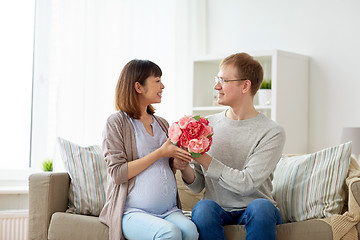 Image showing happy husband giving flowers to his pregnant wife