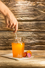 Image showing The bowl with honey on wooden table.The bank of honey stay near wooden spoon