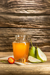 Image showing The bowl with honey on wooden table.The bank of honey stay near wooden spoon