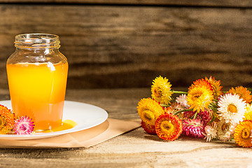 Image showing The bowl with honey on wooden table.The bank of honey stay near wooden spoon