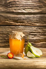 Image showing The bowl with honey on wooden table.The bank of honey stay near wooden spoon