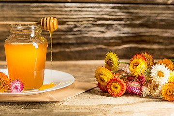 Image showing The bowl with honey on wooden table.The bank of honey stay near wooden spoon