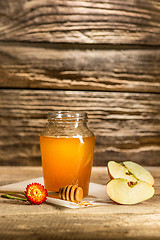 Image showing The bowl with honey on wooden table.The bank of honey stay near wooden spoon