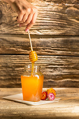 Image showing The bowl with honey on wooden table.The bank of honey stay near wooden spoon