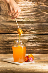 Image showing The bowl with honey on wooden table.The bank of honey stay near wooden spoon