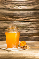 Image showing The bowl with honey on wooden table.The bank of honey stay near wooden spoon