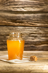 Image showing The bowl with honey on wooden table.The bank of honey stay near wooden spoon