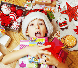 Image showing little cute kid in santas red hat with handmade gifts, toys vint