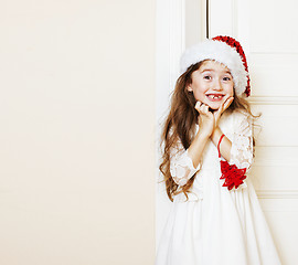 Image showing little cute girl in santas red hat waiting for Christmas gifts. 