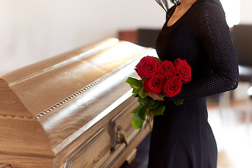 Image showing woman with red roses and coffin at funeral