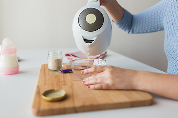 Image showing mother pouring water into bowl for baby cereal