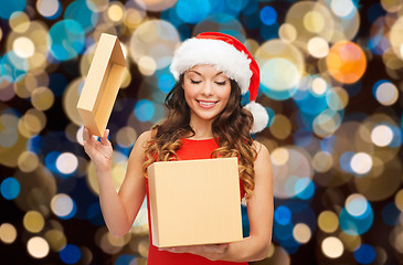 Image showing smiling woman in santa hat opening christmas gift