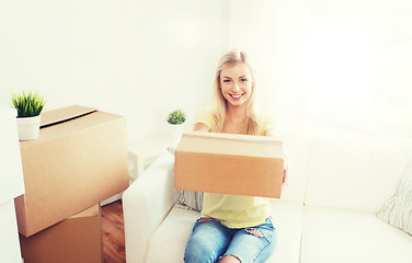 Image showing smiling young woman with cardboard box at home