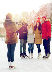 Image showing happy friends with smartphone on ice skating rink