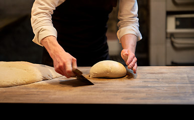 Image showing baker portioning dough with bench cutter at bakery