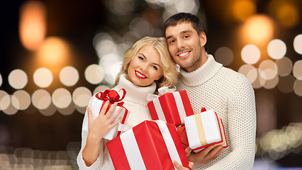 Image showing happy couple in sweaters holding christmas gifts