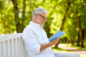 Image showing happy senior man reading book at summer park