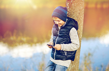 Image showing happy boy playing game on smartphone outdoors