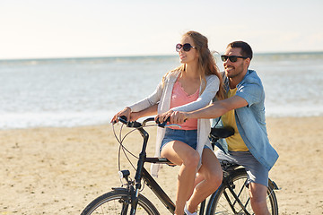 Image showing happy young couple riding bicycle on beach