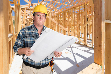 Image showing Male Contractor With House Plans Wearing Hard Hat Inside New Hou