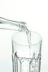 Image showing Pouring water from bottle into glass on white