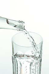 Image showing Pouring water from bottle into glass on white