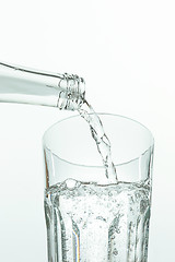 Image showing Pouring water from bottle into glass on white