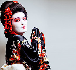 Image showing young pretty geisha in kimono with sakura and red decoration des