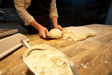 Image showing baker portioning dough with bench cutter at bakery