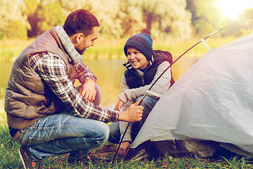 Image showing happy father and son setting up tent outdoors
