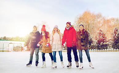 Image showing happy friends ice skating on rink outdoors