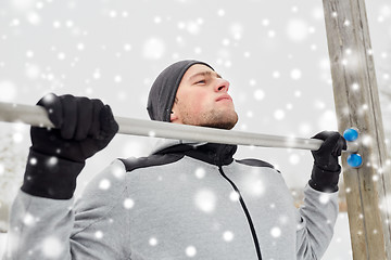 Image showing young man exercising on horizontal bar in winter