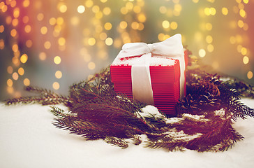 Image showing christmas gift and fir wreath with cones on snow