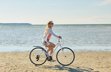 Image showing happy woman riding bicycle along summer beach