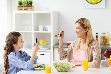 Image showing girl photographing mother by smartphone at home