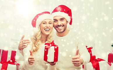 Image showing happy couple with christmas gifts and thumbs up