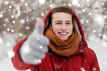 Image showing happy man in winter jacket showing thumbs up