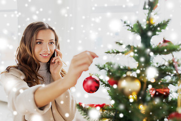 Image showing woman with smartphone decorating christmas tree