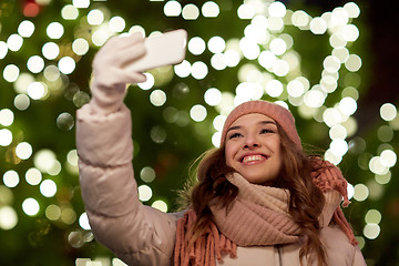 Image showing young woman taking selfie over christmas tree